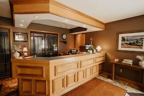 A kitchen with wooden cabinetry, a built-in island, a clock, and a framed landscape painting.