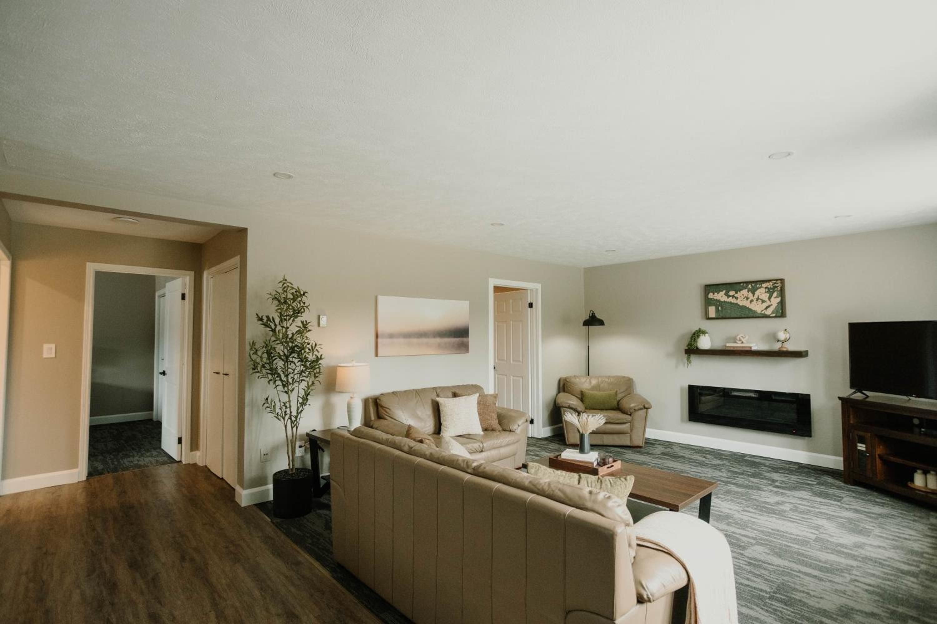 A living room with a sofa, armchairs, a coffee table, a TV, and a fireplace.