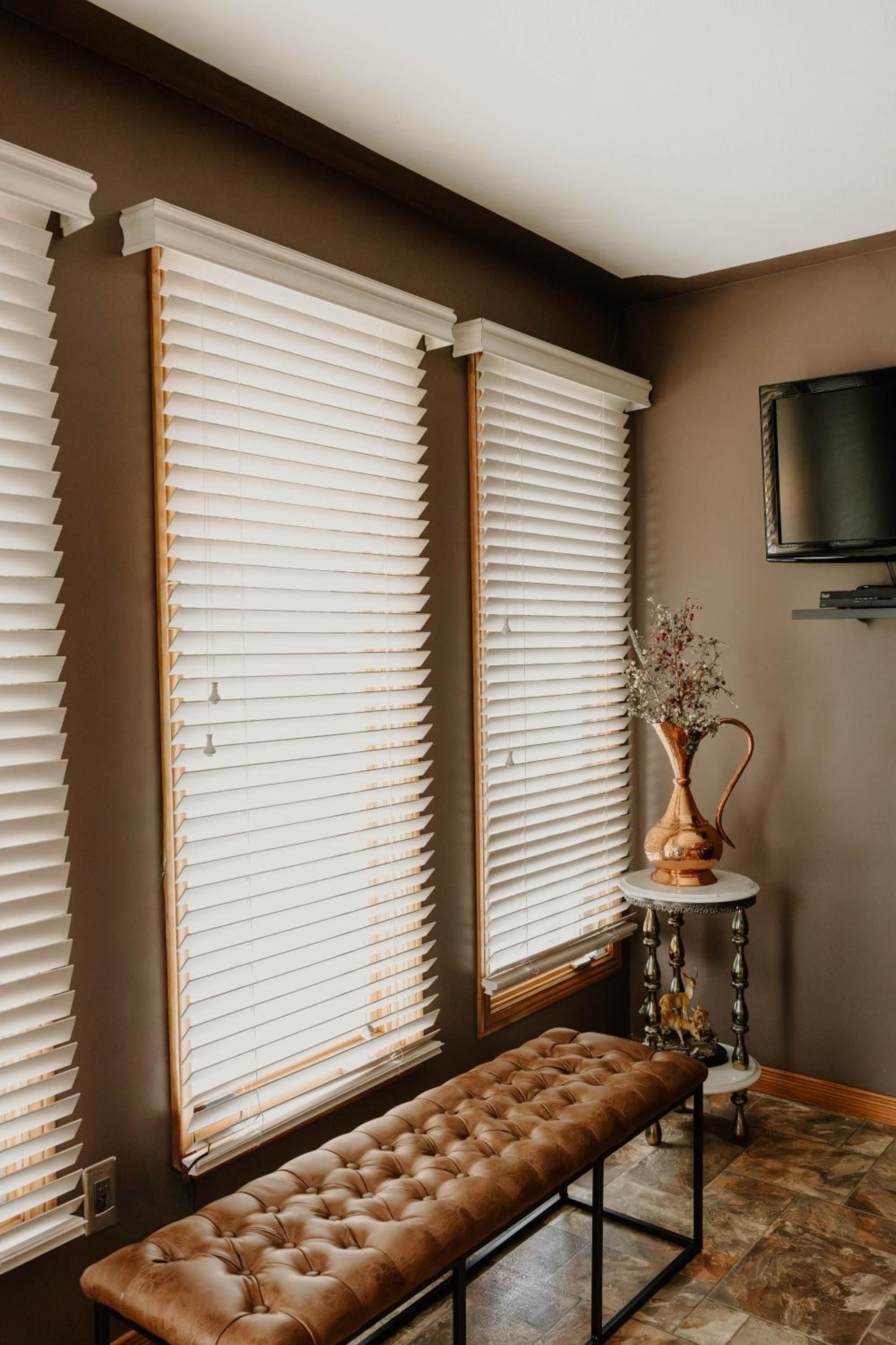 A room with a large window, a bench, and a television mounted on the wall.