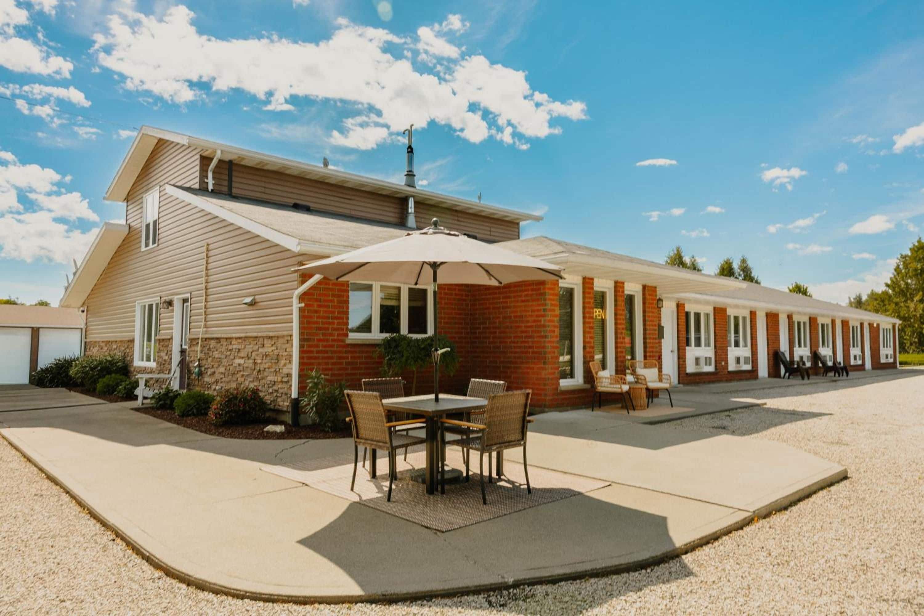 A motel with a patio area, outdoor seating, and a covered walkway.