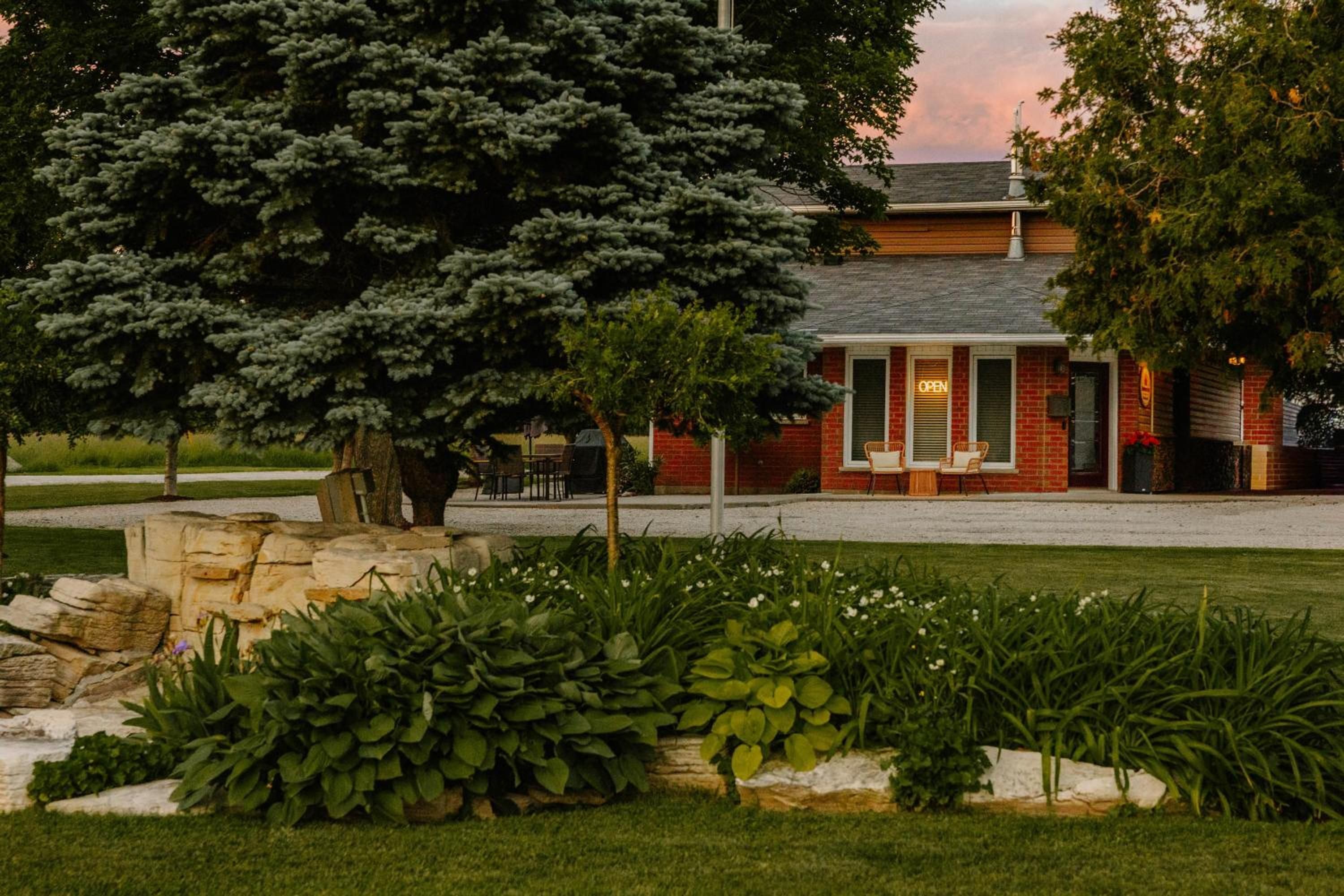 A brick building with a covered patio area, surrounded by well-maintained landscaping and trees.