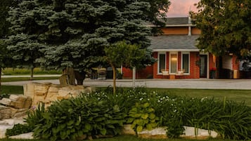 A brick building with a covered patio area, surrounded by well-maintained landscaping and trees.