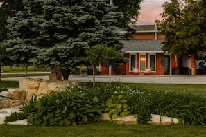 A brick building with a covered patio area, surrounded by well-maintained landscaping and trees.