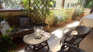 A wicker furniture set with a glass table and candle centerpiece, surrounded by potted plants and a lattice structure. - Hotel Ristorante La Bettola (Sasso Marconi)