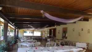 An indoor dining area with tables set for multiple guests, chairs arranged around them, and a ceiling with exposed beams. - Hotel Ristorante La Bettola (Sasso Marconi)