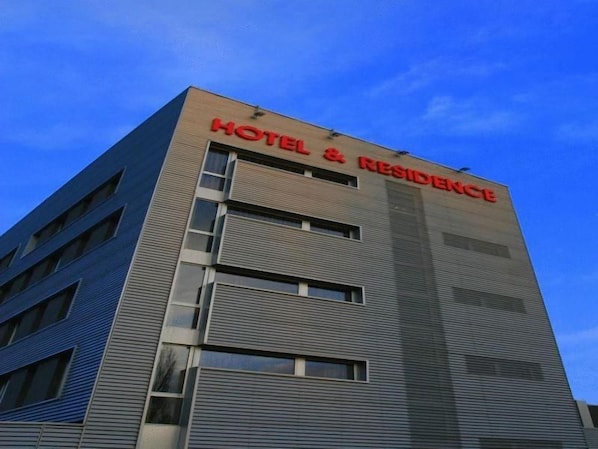 A hotel building with a sign reading 'HOTEL & RESIDENCE' on the facade.