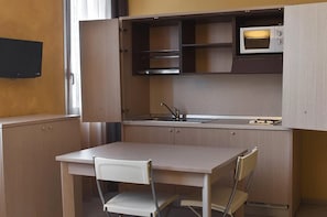A compact kitchenette with a microwave, sink, and cabinets.