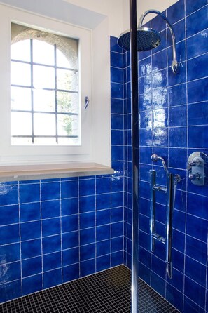 Een badkamer met blauwe tegels, een raam en een douche.
