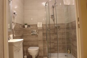 A bathroom with a glass-enclosed shower, a sink, and a toilet.