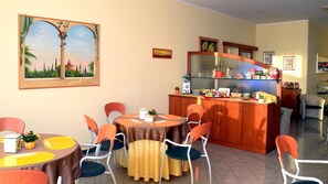 A dining area with round tables, chairs, and a cabinet with kitchenware. - Hotel Sabo' (Argelato)