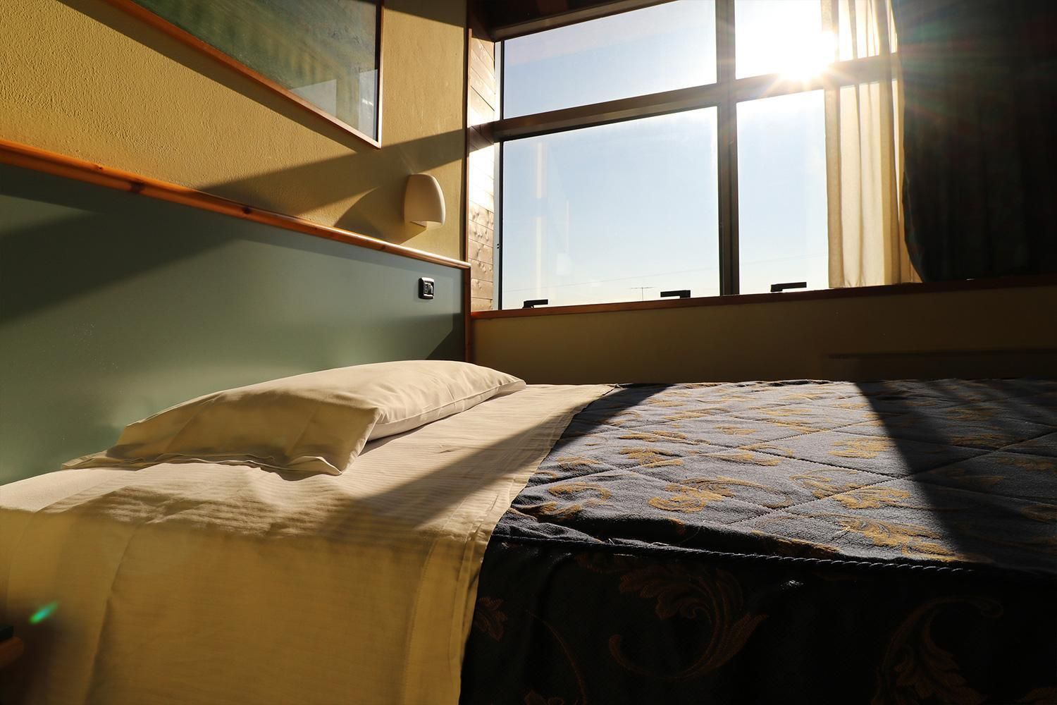 Una stanza con un letto, una finestra e un lampadario a parete.
