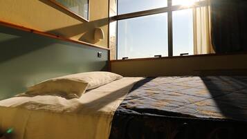 Una stanza con un letto, una finestra e un lampadario a parete.