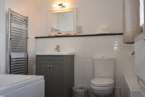 A bathroom with a toilet, sink, and a towel rack.
