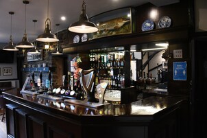 Un bar con múltiples grifos de cerveza, un grifo grande de Guinness y una variedad de botellas al fondo.