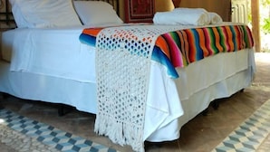 A bedroom with a bed, a patterned wall hanging, a decorative wall piece, and a patterned floor. - Zazen Pousada By Santoregano (Maceió)