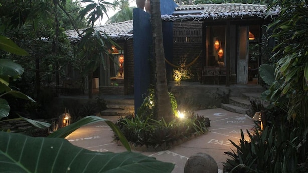A courtyard with a traditional building, stone pathway, and lush greenery. - Zazen Pousada By Santoregano (Maceió)