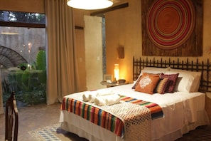 A bedroom with a bed, a nightstand, a lamp, and a decorative wall piece. - Zazen Pousada By Santoregano (Maceió)