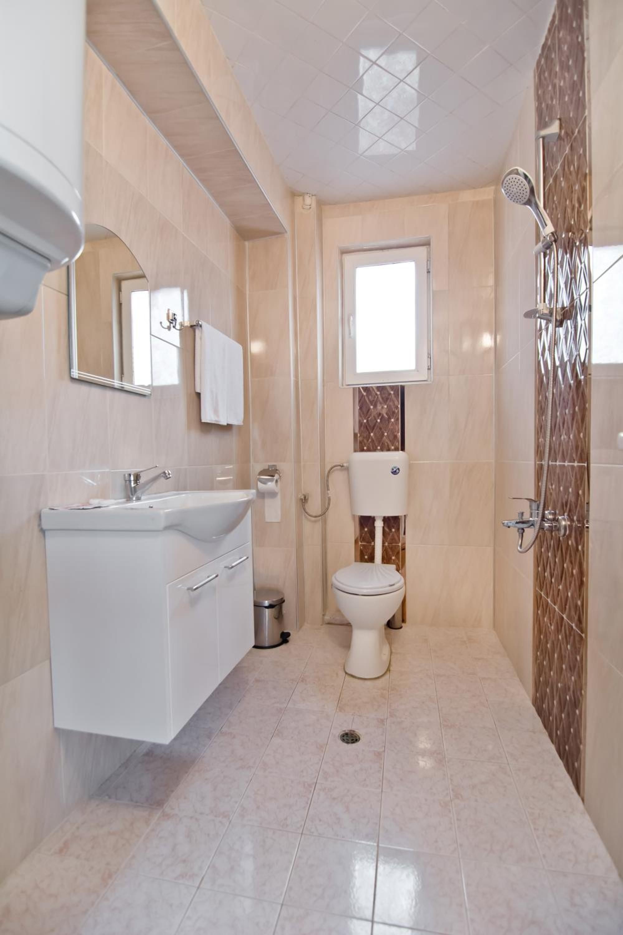 A modern bathroom with a white vanity, a toilet, and a shower area.