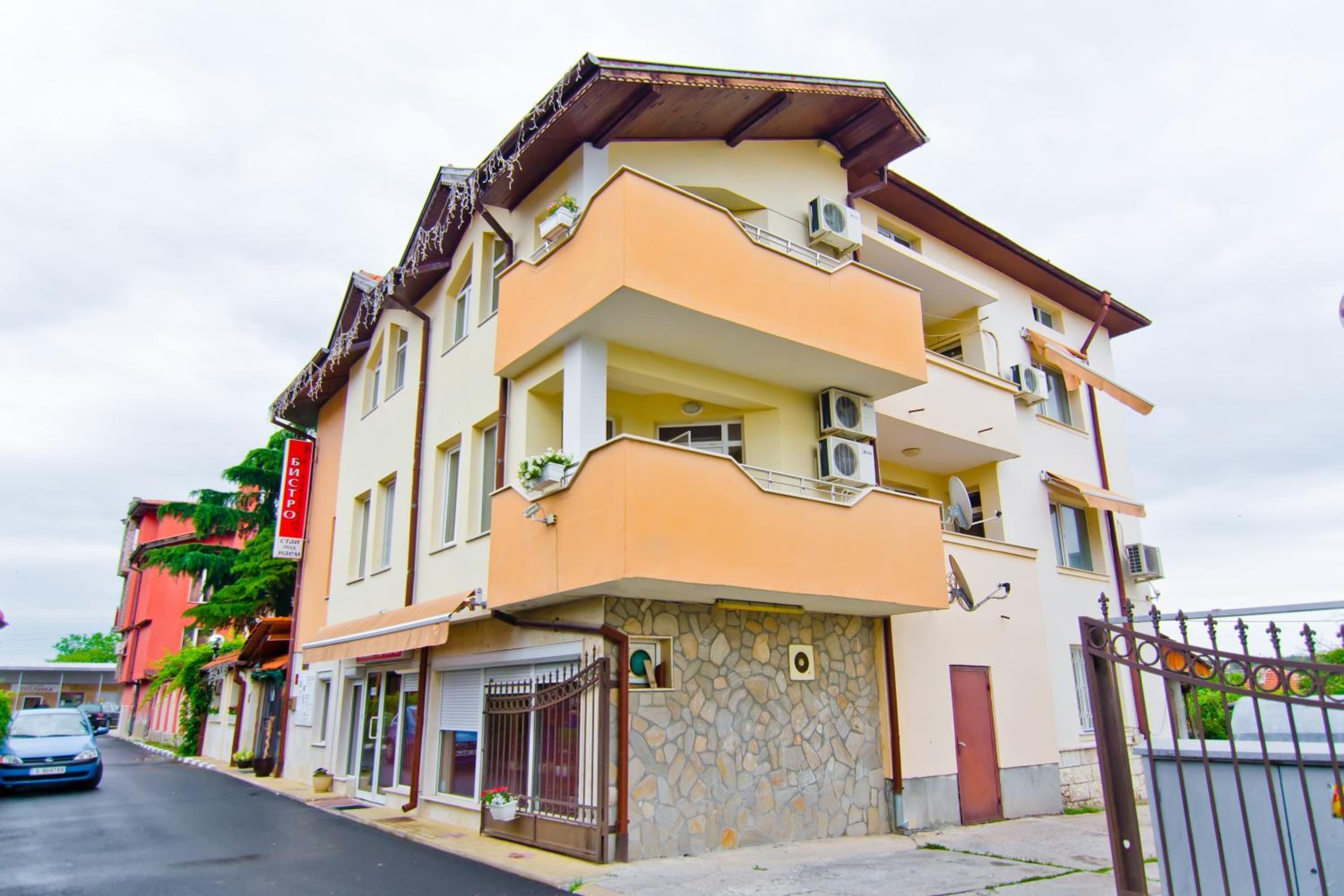 Um edifício com várias andares, varandas, fachada de pedra e entrada com portão.