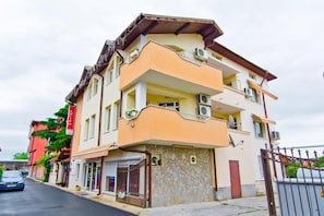 Un immeuble à plusieurs étages, doté de balcons, d’une façade en pierre et d’une entrée fermée par un portail.