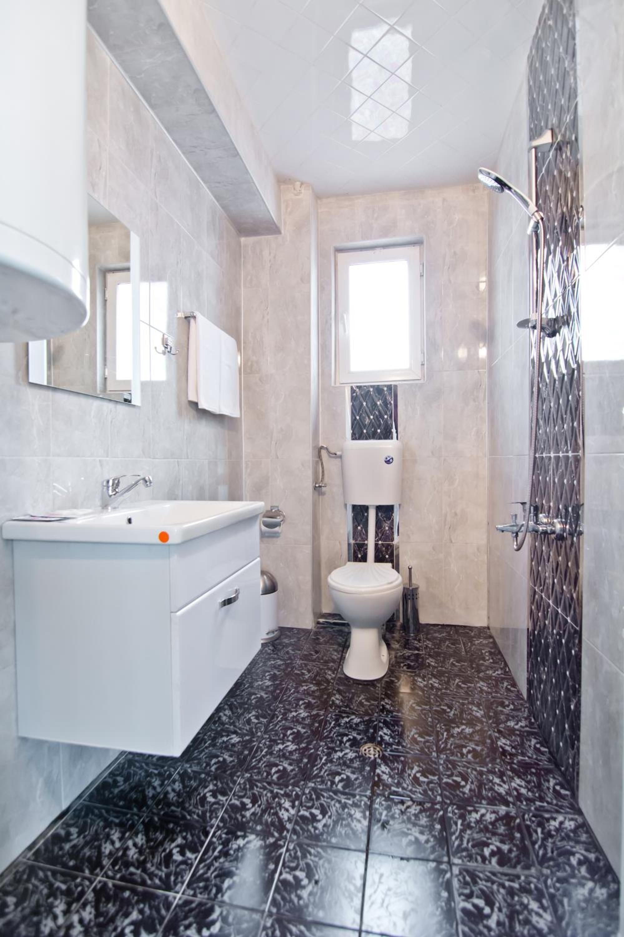 Ein modernes Badezimmer mit einem weißen Waschtisch, einer Toilette und einer Duschkabine.
