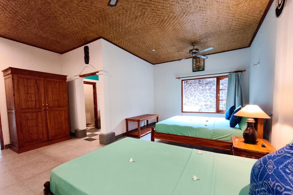 A room with two beds, a wardrobe, a ceiling fan, and a window with a view.