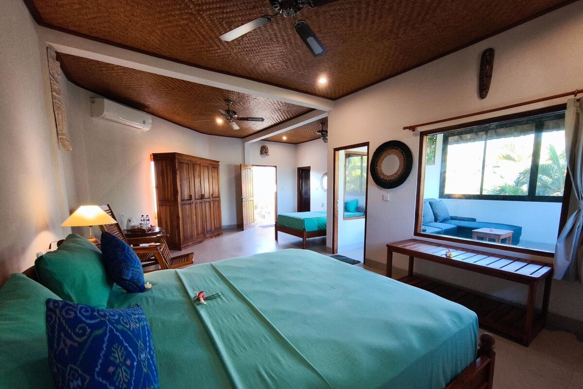 A bedroom with a bed, a desk, a chair, a window, and a view of the outdoors.