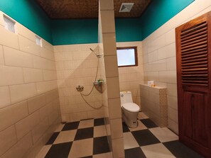 Un baño con piso a cuadros, ducha, inodoro y ventana.