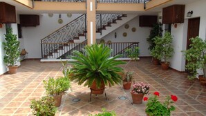 A spacious indoor area with a tiled floor, potted plants, and a staircase with decorative railings.
