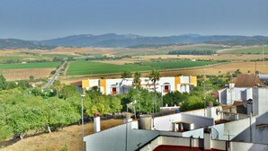 A rural landscape with a road, fields, and a building with a red door.