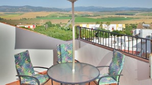 A terrace with a table and chairs, an umbrella, and a view of the countryside.