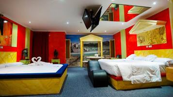 A hotel room with two beds, a TV, a mural, and a small table.