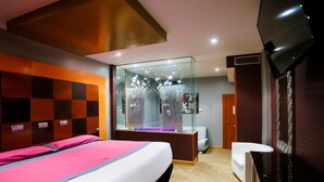 A modern hotel room with a large bed, a glass partition, a desk, and a chair. - Motel Venus Valladolid (Villanubla)