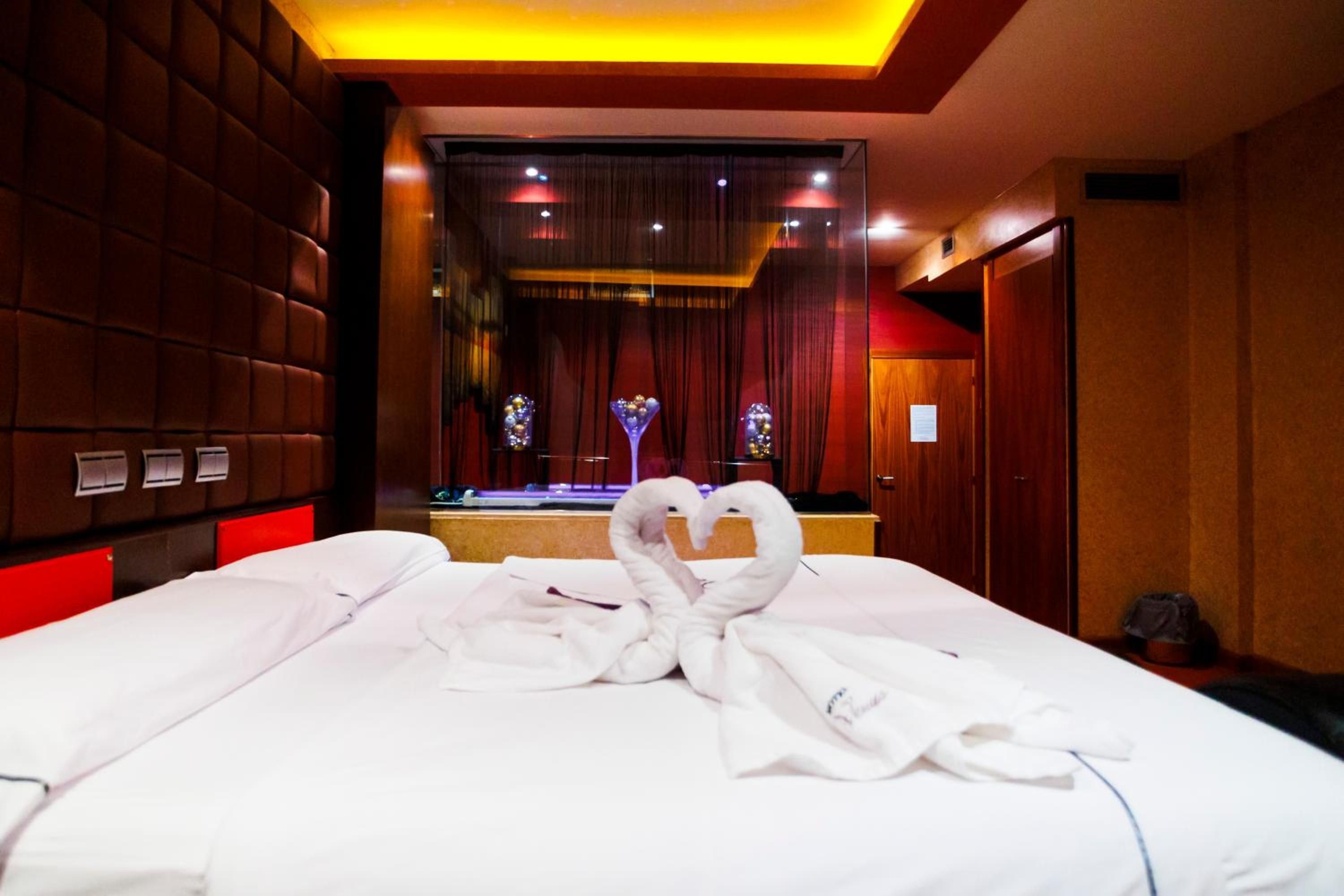 A hotel room with a large bed, a mirror, and a red-lit ceiling.