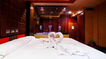 A hotel room with a large bed, a mirror, and a red-lit ceiling.