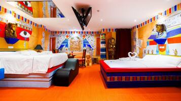 A hotel room with two beds, a large mirror, and walls decorated with Egyptian-themed artwork.