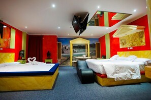 Una habitación de hotel con dos camas, televisión, un mural y una mesita.