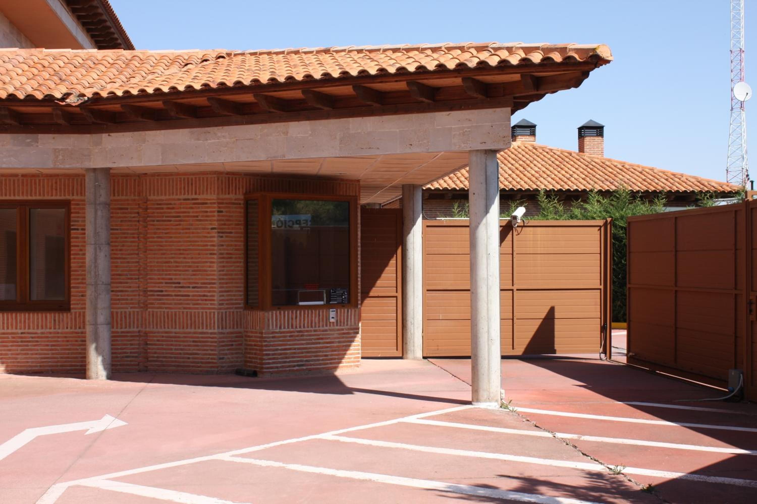 Un edificio con techo de tejas, paredes de ladrillo y un porche con puerta y ventana.