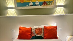 A hotel room with a bed, pillows, a painting, and a towel. - Pousada Praia Brava (Matinhos)