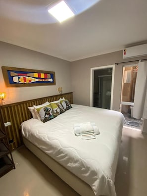 Una habitació d'hotel amb un llit, almoines, una obra d'art a la paret, una taula de nit i una finestra.
