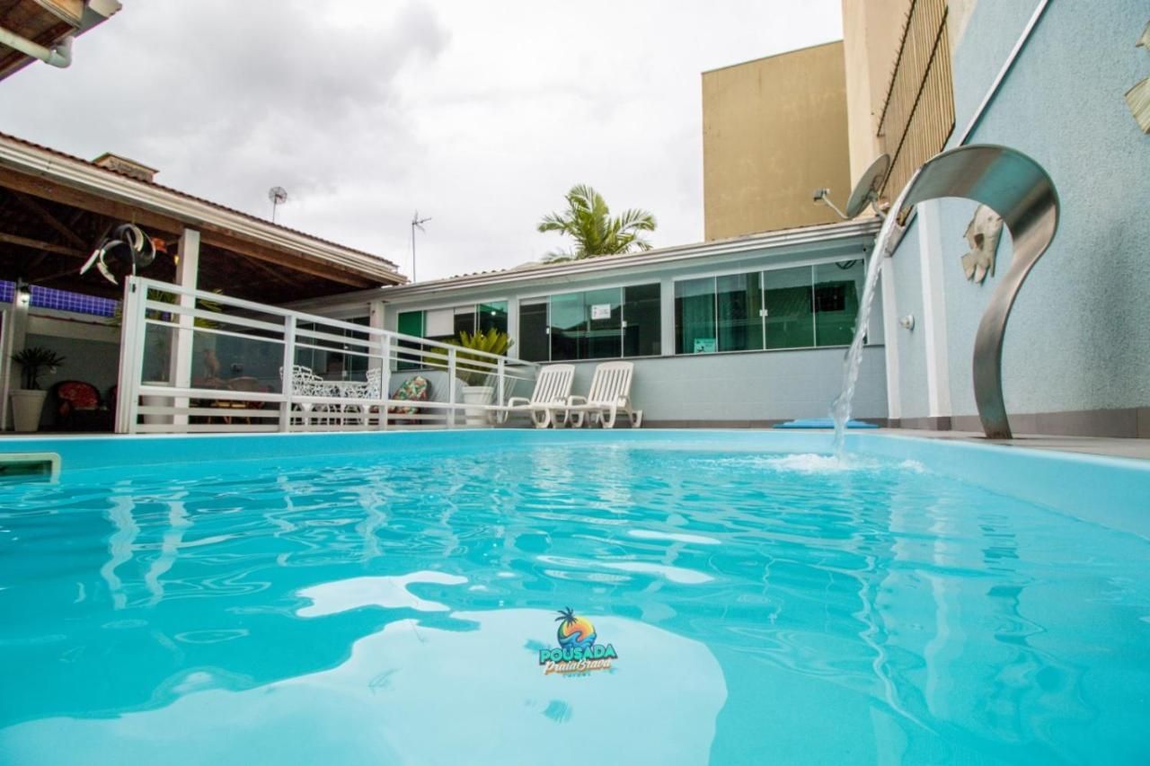 Una piscina con fuente, sillas de descanso blancas y un edificio con ventanas amplias.