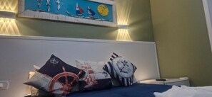 A bed with multiple pillows, a wall with a painting, and a bedside table.