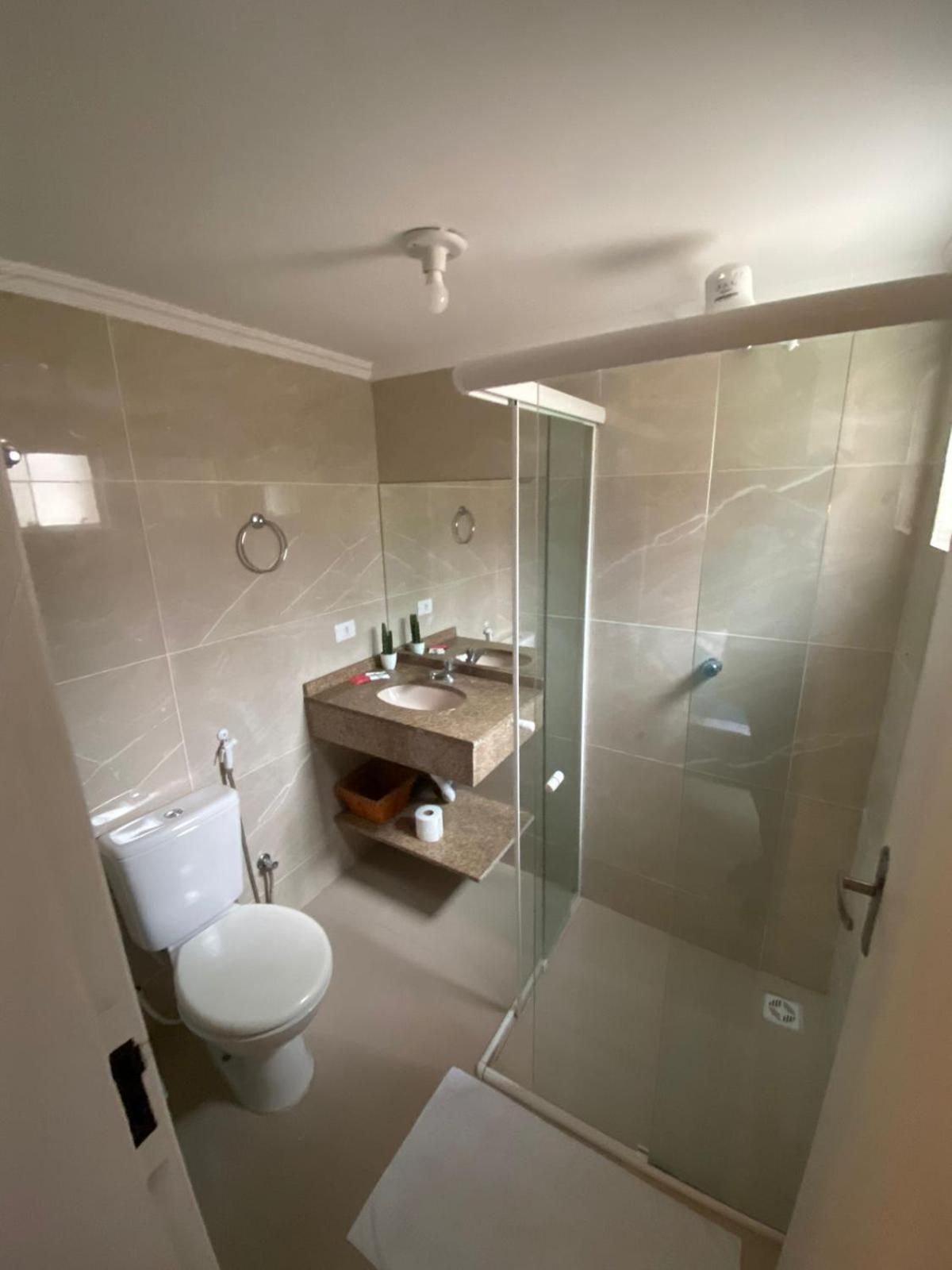 A bathroom with a toilet, a sink, a glass shower enclosure, and a mirror.