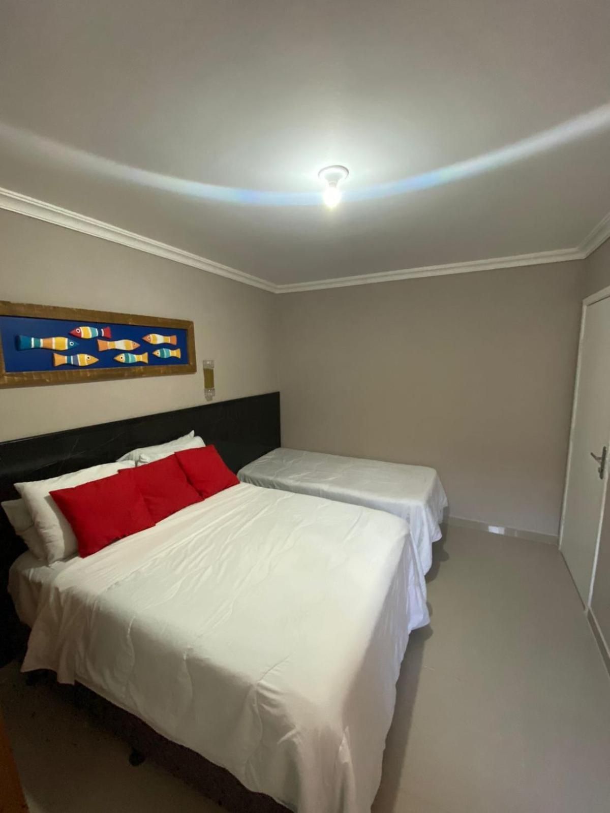Quarto de hotel com duas camas, uma luminária no teto e uma obra de arte na parede.