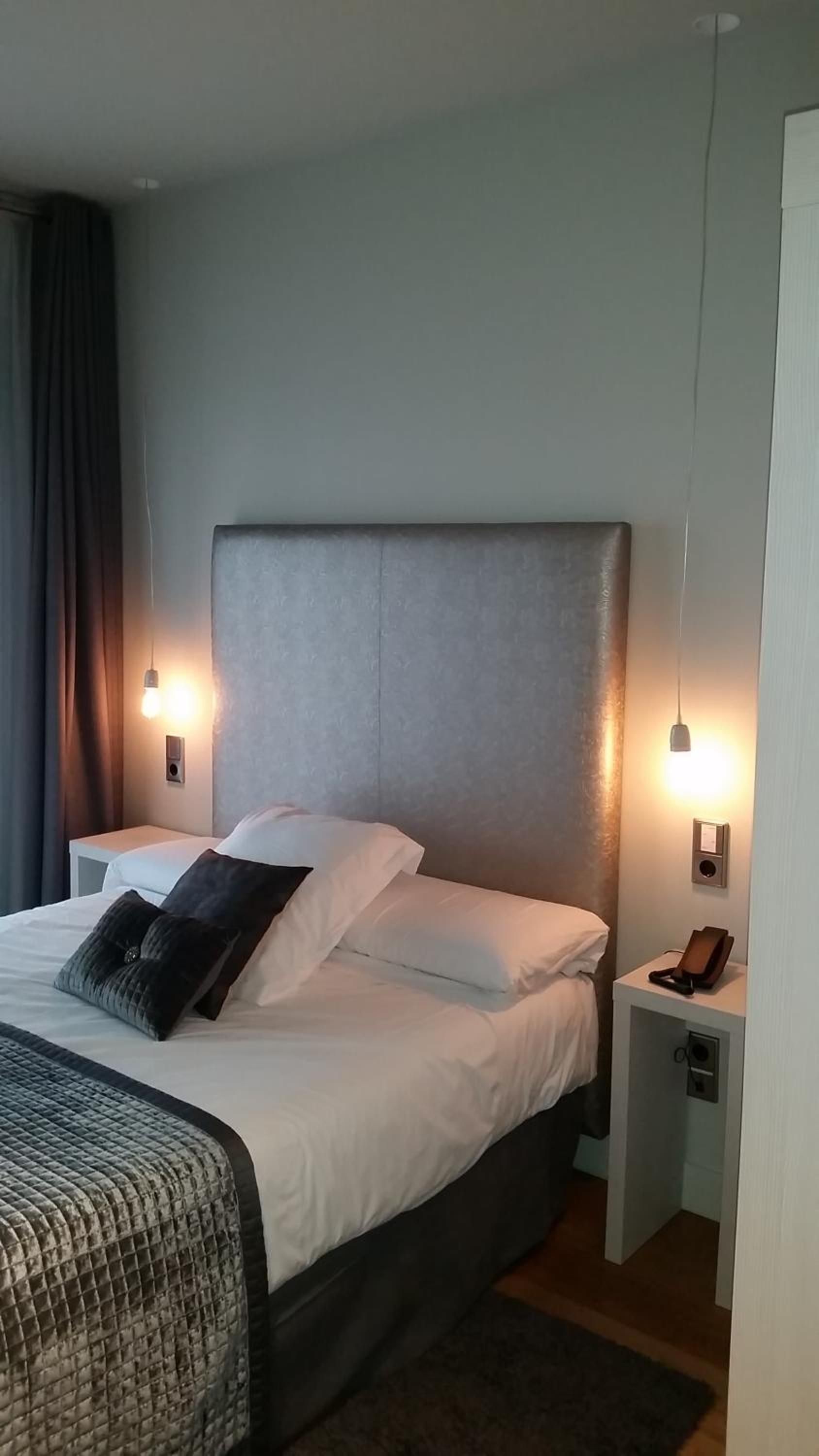 A hotel room with a large bed, two bedside tables, and a nightstand with a phone.
