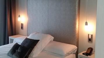 A hotel room with a large bed, two bedside tables, and a nightstand with a phone.