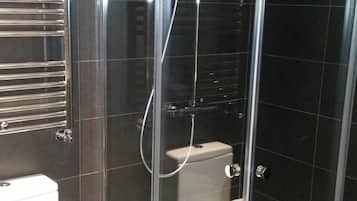 A modern bathroom with a glass-enclosed shower, a toilet, and a towel rack.