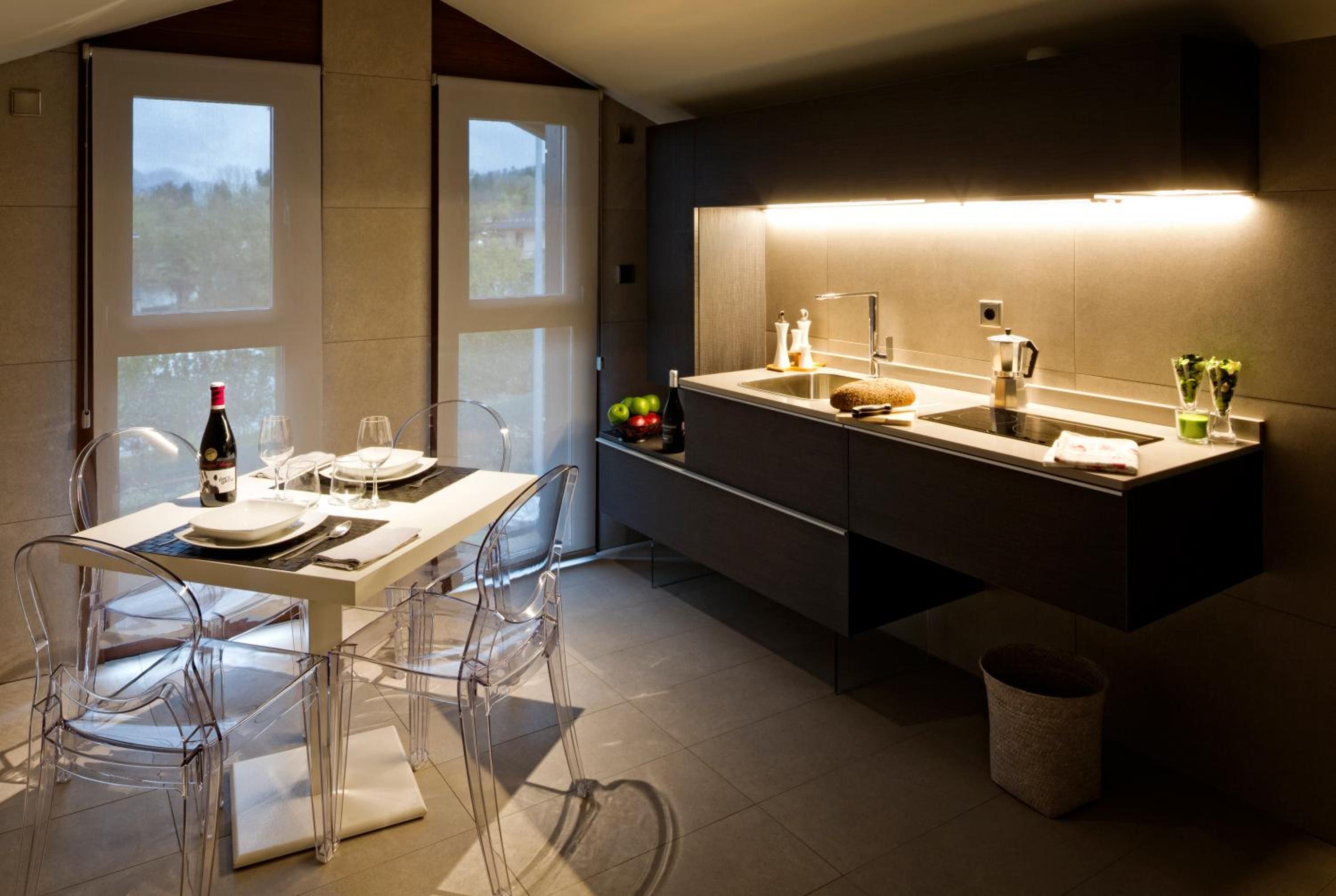 A modern kitchen with a dining area, featuring a large window, a built-in oven, and a sink.