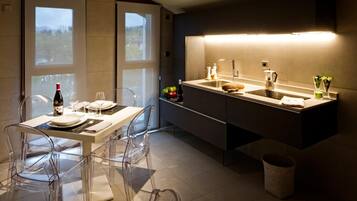 A modern kitchen with a dining area, featuring a large window, a built-in oven, and a sink.