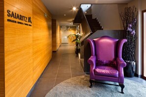 A hotel lobby with a wooden wall, a purple armchair, and a staircase. - Saiaritz (Amurrio)